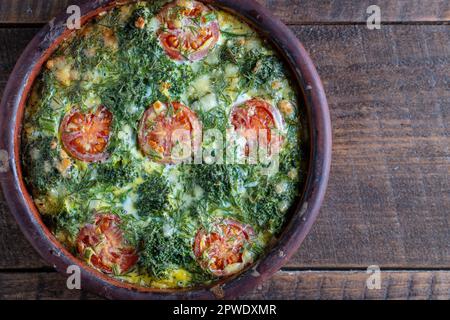 Bol en céramique avec frittata de légumes, simple nourriture végétarienne. Frittata avec oeuf, tomate, poivre, oignon, brocoli vert et fromage sur table en bois, clo Banque D'Images