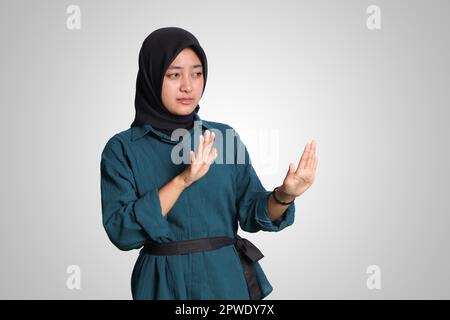 Portrait d'une femme musulmane asiatique gaie avec hijab formant un geste de main pour éviter quelque chose. Concept publicitaire. Image isolée sur fond blanc Banque D'Images