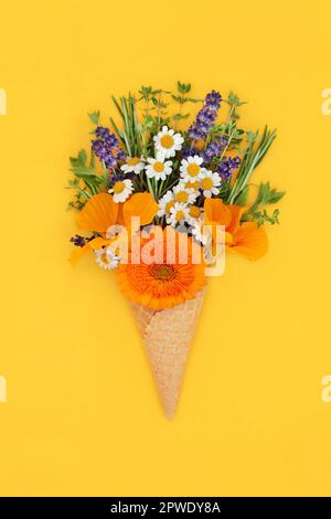 Été fleurs comestibles et herbes fraîches dans la glace gaufre cône minimal surréaliste nature concept alimentaire sur fond jaune vif. Espace de copie de la pose en barre. Banque D'Images