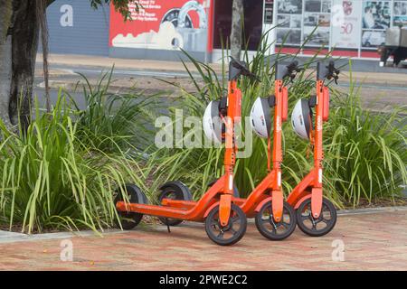 Bundaberg, Queensland, Australie, 10 octobre 2022. E-trottinettes avec casques alignés prêt à louer électroniquement sur un sentier urbain. Banque D'Images