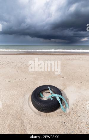 Alter Reifen am Strand mit Netzresten, vieux pneu sur la plage avec des morceaux de filet Banque D'Images