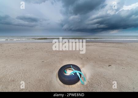 Alter Reifen am Strand mit Netzresten, vieux pneu sur la plage avec des morceaux de filet Banque D'Images
