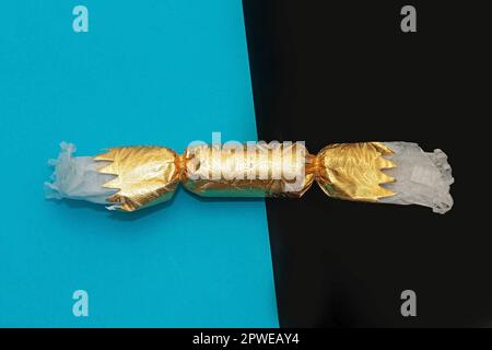 Papillote de Noël de fête enveloppée dans un tube en papier doré sur fond de couleur recto verso Banque D'Images