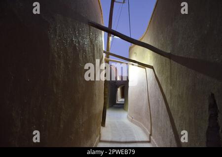 Allée illuminée à travers les murs d'argile de la vieille ville de Yazd dans la lumière du soir Banque D'Images