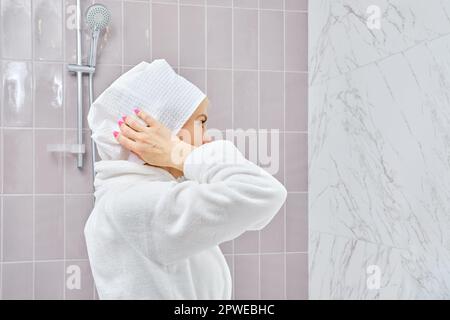 Femme d'âge moyen en peignoir enveloppant ses cheveux dans une serviette après la douche Banque D'Images