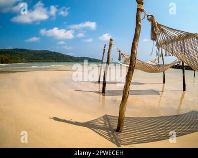 Trois berceau de corde vide suspendu sur les poteaux en bois sur la plage de sable, île et fond bleu ciel, vue fisheye. Magnifique ombre du berceau suspendu o Banque D'Images