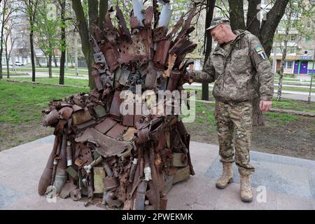 15 avril 2023, Zaporizhjhia, Ukraine : un soldat de l'armée ukrainienne regarde le trône de fer de l'est dans le centre de Zaporizhjhia. Le trône de fer de l'est à Zaporizhjhia, en Ukraine, fait de véritables machines militaires, épaves et coquilles. Elle a été prise aux positions des forces armées d'Ukraine dans la ville d'Avdiivka, dans la région de Donetsk, au cours de l'hiver 2016. Le trône de fer de l'est a été installé dans la ville de Zaporizhzhia avec l'appui des députés locaux anciens combattants de guerre. Il honore la volonté exceptionnelle du peuple ukrainien de gagner. Les auteurs de cette sculpture en métal étaient inspi Banque D'Images