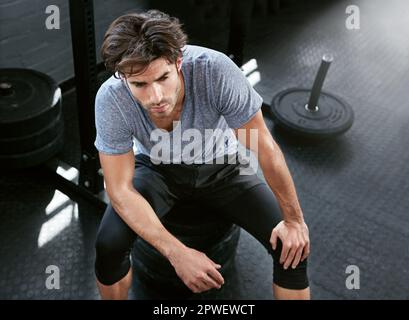 Il n'y a qu'un seul temps pour un reniflard rapide. un jeune homme qui fait une pause pour s'entraîner avec des poids dans la salle de gym. Banque D'Images