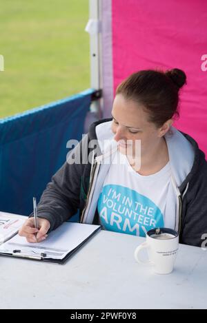 Femme volontaire à Race for Life à Milton Keynes écrivant sur un presse-papiers Banque D'Images