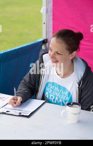 Femme volontaire à Race for Life à Milton Keynes écrivant sur un presse-papiers Banque D'Images