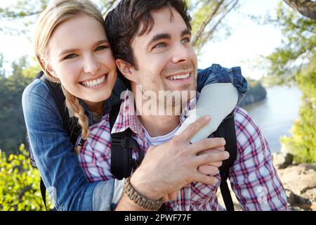 HES un randonneur lourd. Une jeune femme heureuse embrassant son petit ami pendant qu'ils passent du temps ensemble à l'extérieur. Banque D'Images