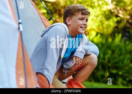 Le bonheur est en voyage de camping. un jeune garçon regardant hors de sa tente. Banque D'Images