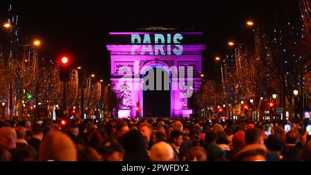 Paris, France - 1 janvier 2023 : foule rassemblée sur les champs Elysées à Paris pour célébrer le passage à 2023 avec un feu d'artifice au-dessus de l'Arc Banque D'Images