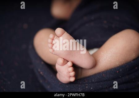 Bébé de petite taille pieds nus croisés sur une couverture bleu marine. vue rapprochée du pied de bébé le bébé est enveloppé confortablement dans une couverture bleue. nouveau-b Banque D'Images