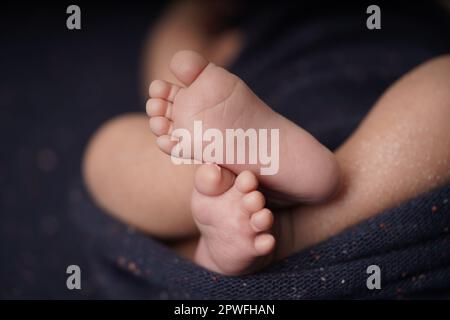 Bébé de petite taille pieds nus croisés sur une couverture bleu marine. vue rapprochée du pied de bébé le bébé est enveloppé confortablement dans une couverture bleue. nouveau-b Banque D'Images