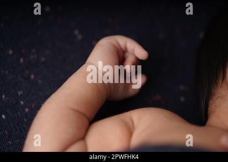 Corps et mains de bébé sur une couverture bleu marine. vue rapprochée de la main mignonne du bébé le bébé repose confortablement dans une couverture bleue. Banque D'Images