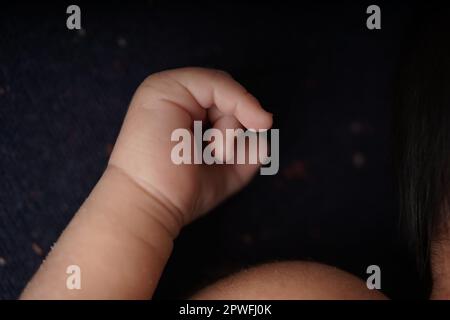 Corps et mains de bébé sur une couverture bleu marine. vue rapprochée de la main mignonne du bébé le bébé repose confortablement dans une couverture bleue. Banque D'Images