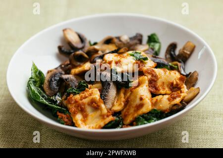 Raviolis végétaliens aux champignons, aux épinards et à la sauce tomate séchée au soleil. Banque D'Images