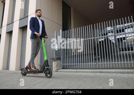 Homme d'affaires à bord d'un scooter moderne sur la rue de la ville, espace pour le texte Banque D'Images