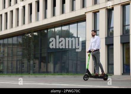 Homme d'affaires à bord d'un scooter moderne sur la rue de la ville, espace pour le texte Banque D'Images