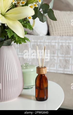 Désodorisant et vase en roseau aromatique avec bouquet sur table blanche dans la chambre Banque D'Images