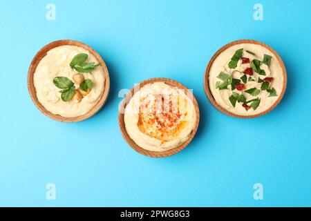 Différents types de houmous savoureux dans des bols sur fond bleu clair, plat Banque D'Images