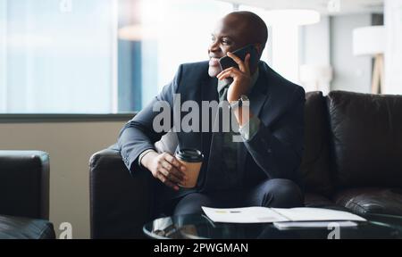 Vous recevrez toujours de bonnes nouvelles si vous êtes un travailleur acharné. un homme d'affaires parlant sur son téléphone portable tout en étant assis dans un bureau moderne. Banque D'Images