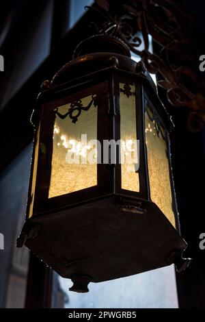 Lampadaire couvert de poussière, rétroéclairé par le soleil du soir suspendu sur un mur Banque D'Images