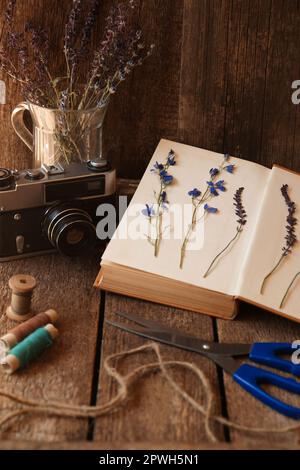 Composition avec de belles fleurs séchées et appareil photo vintage sur table en bois Banque D'Images