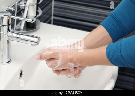 Homme se lavant les mains avec du savon dans le lavabo de la salle de bains, gros plan Banque D'Images