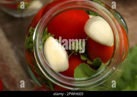 Pot en verre avec légumes, herbes et saumure sur table, gros plan Banque D'Images