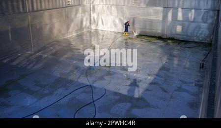 26 avril 2023, Bavière, Nuremberg: Michael, superviseur de quart et maître de piscine à Stadionbad, utilise un nettoyeur haute pression pour enlever les débris liés aux intempéries tels que les algues ou les feuilles de la piscine de plongée vide à Stadionbad pendant les travaux de nettoyage en préparation de la saison 2023 piscine extérieure. Selon les conditions météorologiques, les premières piscines extérieures devraient ouvrir début mai, d'autres le suivant au milieu du mois, selon plusieurs villes bavaroises et des exploitants de piscines municipales. Les prix d'entrée restent stables dans de nombreux endroits, mais de nombreux exploitants de piscine se plaignent de la faiblesse du personnel Banque D'Images