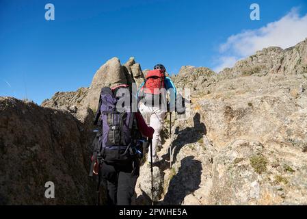 Alpinistes méconnaissables remontant un sentier au milieu d'un paysage de montagnes rocheuses à Los Gigantes, Cordoue, Argentine, une destination touristique idéale. Banque D'Images