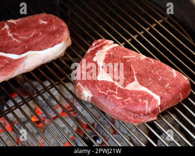 Steak de bœuf cru sur le gril râpez sur le grill au charbon de bois, en préparant des steaks de bœuf sur le barbecue Banque D'Images