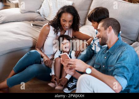 Les vidéos de chat drôle sont notre favori. une famille de quatre personnes regardant quelque chose sur un téléphone portable Banque D'Images