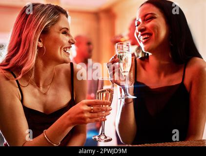 Sœurs pour la vie. deux jeunes femmes gaies bavardent tout en prenant un verre dans un bar le soir Banque D'Images