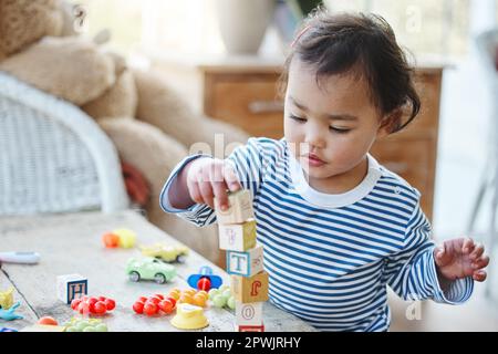 Garder ses petites mains occupées. une adorable petite fille jouant avec ses jouets à la maison Banque D'Images