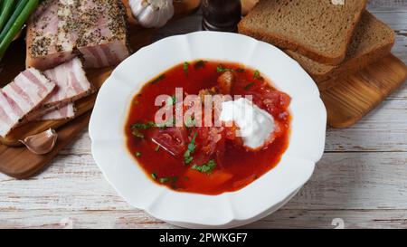 Borscht traditionnel ukrainien . Assiette blanche de soupe de racine de betterave rouge borsch à la crème blanche, oignon vert, filet de porc salé (salo). Déli Beet Root Banque D'Images