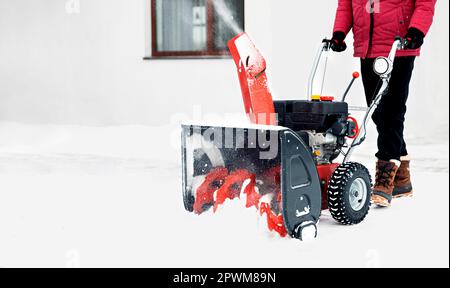 Souffleuse à neige alimentée par l'essence en action. Homme à l'extérieur devant la maison utilisant une souffleuse à neige. Déneigement, assistant de fraise en hiver à l'extérieur h Banque D'Images