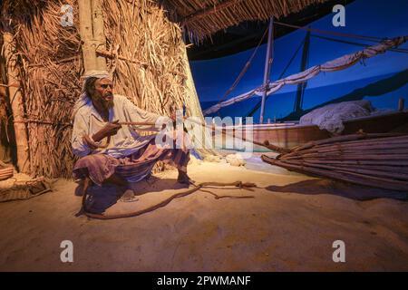 Un pêcheur tirant une ligne de corde de son filet, dispositif de capture de bois sur la plage, voilier en arrière-plan. Un diorama représentant une scène du passé des eau, Banque D'Images