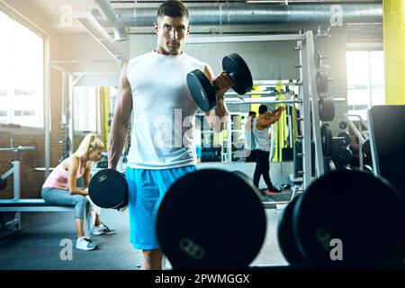 Ne laissez personne prendre votre détermination. un jeune homme s'entraîner seul dans la salle de gym. Banque D'Images