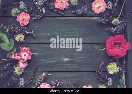 Fleurs dans un cercle sur fond en bois. Carte postale pour les vacances. Roses, géraniums, lavande, sauge et châtaignes poilues sont placés le long des bords Banque D'Images