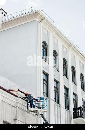 Ouvrier de construction dans la peinture de seau de levage, de restaurer la façade historique du bâtiment. Banque D'Images