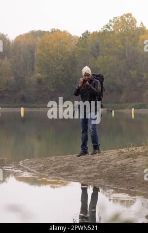 Portrait de voyageur homme au lac en automne prendre une photo avec l'appareil photo numérique. Photo de haute qualité Banque D'Images