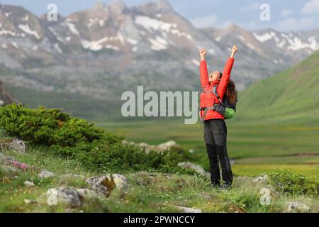 Randonneur excité dans les bras rouges levant célébrant des vacances dans la nature avec un beau paysage en arrière-plan Banque D'Images