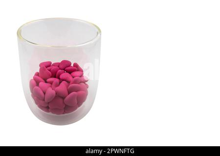 Verre avec bonbons roses en forme de coeur (gros plan) isolés sur fond blanc. Vue de dessus Banque D'Images