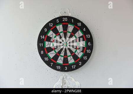 Vieux dartboard perforé par des fléchettes sur un mur gris. Arrière-plan d'une vieille cible ronde de merde dans les trous et les coupes pour le jeu de fléchettes symbole de précision et de suc Banque D'Images