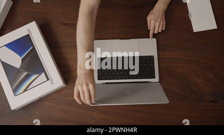 Saint-Pétersbourg, Russie - Circa décembre, 2022 : homme déballant le nouveau macbook pro 14 m1 pro puce sur la table en bois, contenu de marque Banque D'Images
