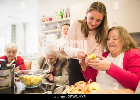 Femme âgée avec une fille coupant la pomme au repos à la maison Banque D'Images