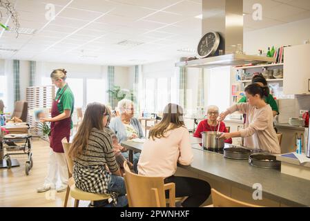 Infirmière avec des femmes et des filles âgées préparant de la nourriture à la maison de repos Banque D'Images